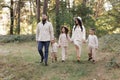 Young mother, father with daughter and sons are walking, having fun in autumn forest. Family holding hands enjoying time Royalty Free Stock Photo