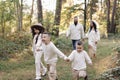 Young mother, father with daughter and sons are walking, having fun in autumn forest. Family holding hands enjoying time Royalty Free Stock Photo