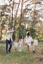 Young mother, father with daughter and sons are walking, having fun in autumn forest. Family holding hands enjoying time Royalty Free Stock Photo