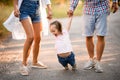 Young mother and father hold the hands of child and swing her