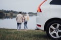 Young Mother and Father with Their Toddler Daughter Standing Outdoors Near the Lake, Concept of Family Road Trip on a Royalty Free Stock Photo