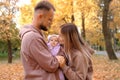 Young mother and father are walking with a newborn baby in the autumn park. Mother kissing newborn daughter Royalty Free Stock Photo