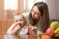 Young mother feeding baby son with fruit puree Royalty Free Stock Photo