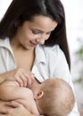 Young mother feeding breast her baby at home in white room Royalty Free Stock Photo