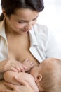 Young mother feeding breast her baby at home in white room Royalty Free Stock Photo