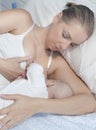 Young mother feeding breast her baby laying in her bedroom Royalty Free Stock Photo