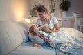 Young mother feeding her baby from bottle in bed at night Royalty Free Stock Photo