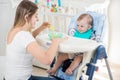 Young mother feeding her baby boy with fruit sauce Royalty Free Stock Photo