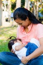 Young mother feeding her baby in the park Royalty Free Stock Photo