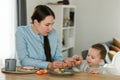 Young mother feeding her baby son with fruit Royalty Free Stock Photo