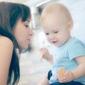 Beautiful mother playing with her beautiful child , the child eats the cookie and laughs