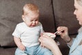 Young mother feeds the baby. Small baby refuse to eat food and crying over feeding time