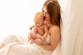 A young mother gently embraces a child in her arms while sitting on the window, the concept of mother`s love and care for the Royalty Free Stock Photo