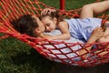 Young mother gently hugs her little daughter lying together on a hammock, enjoying the time in a place on a nature on a warm sunny Royalty Free Stock Photo