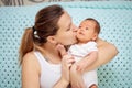 Young mother gently hugs her newborn baby. Mothers Day. Woman kisses her baby