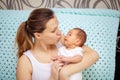 Young mother gently hugs her newborn baby. Mothers Day. Woman kisses baby