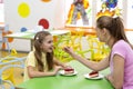 Young mother giving piece of tasty cheesecake to her teen daughter in cafe at kids entertainment centre Royalty Free Stock Photo