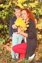 Young mother and handsome little son with yellow maples