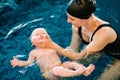 Young mother, happy little girl in the pool. Teaches infant child to swim. Enjoy the first day of swimming in water. Mom holds Royalty Free Stock Photo