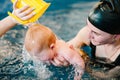 Young mother, happy little girl in the pool. Teaches infant child to swim. Enjoy the first day of swimming in water. Mom holds Royalty Free Stock Photo