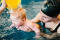 Young mother, happy little girl in the pool. Teaches infant child to swim. Enjoy the first day of swimming in water. Mom holds Royalty Free Stock Photo