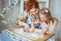 Young mother help to roll a dough to her daughter Royalty Free Stock Photo