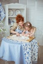 Young mother help to roll a dough to her little daughter Royalty Free Stock Photo