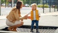 Young mother helping her baby son jumping on trampoline at playground. Happy parenting, family having time together, kids and Royalty Free Stock Photo