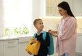 Young mother helping her little child get ready for school in kitchen Royalty Free Stock Photo