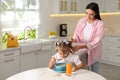 Young mother helping her little child get ready for school in kitchen Royalty Free Stock Photo