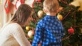 Portrait of young mother helping her little son decorating Christmas tree in living room Royalty Free Stock Photo