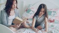 Young mother helps her little cute daughter with homework for elementary school. Loving mom reading a book and girl Royalty Free Stock Photo