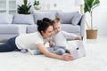 Young mother and her adorable daughter are using laptop while lying on the floor. Royalty Free Stock Photo