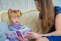 Young mother and her baby daughter looking photobook