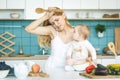 Young mother with her baby daughter in a modern kitchen setting. Young attractive cook woman desperate in stress Royalty Free Stock Photo