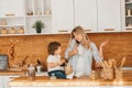 Young mother with her baby daughter in a modern kitchen setting. Young attractive cook woman desperate in stress, tired Royalty Free Stock Photo