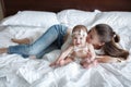 Young mother and her baby daughter playing togerher on the bed at home Royalty Free Stock Photo