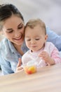 Young mother with her baby eating fruit salad Royalty Free Stock Photo
