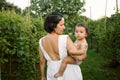 Young mother with her baby girl walking through a vineyard in summer playing and tasting fruits before the harvest at sunset. Royalty Free Stock Photo