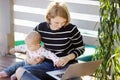 Young mother with her baby girl working or studying on laptop Royalty Free Stock Photo