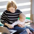 Young mother with her baby girl working or studying on laptop Royalty Free Stock Photo