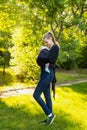 A young mother with her baby in a sling scarf is standing in a sunlight. Newborn carrier. Winding sling for carrying a child Royalty Free Stock Photo