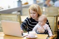 Young mother with her baby working or studying on her laptop Royalty Free Stock Photo