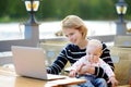 Young mother with her baby working or studying on her laptop Royalty Free Stock Photo