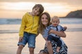 Young mother with her beautiful children, enjoying the sunset over the ocean on a low tide in Devon Royalty Free Stock Photo