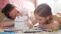 Young mother and her beautiful daughter, paint a paper house, lying on the floor at home, lifestyle, creativity