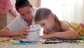 Young mother and her beautiful daughter, paint a paper house, lying on the floor at home, lifestyle, creativity