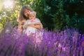 Young mother with her child outdoor garden with lavender flowers and sunshine