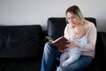 Young mother and her child reading a book, the concept of early development, indoor Royalty Free Stock Photo