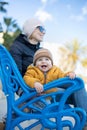 Young mother with her cute infant baby boy child on bench in city park. Royalty Free Stock Photo